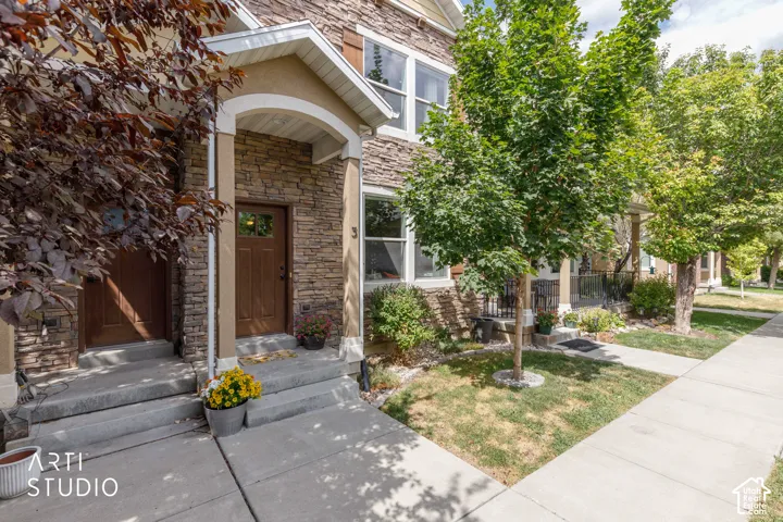 Stone facade with a covered entry, concrete steps, and a sidewalk