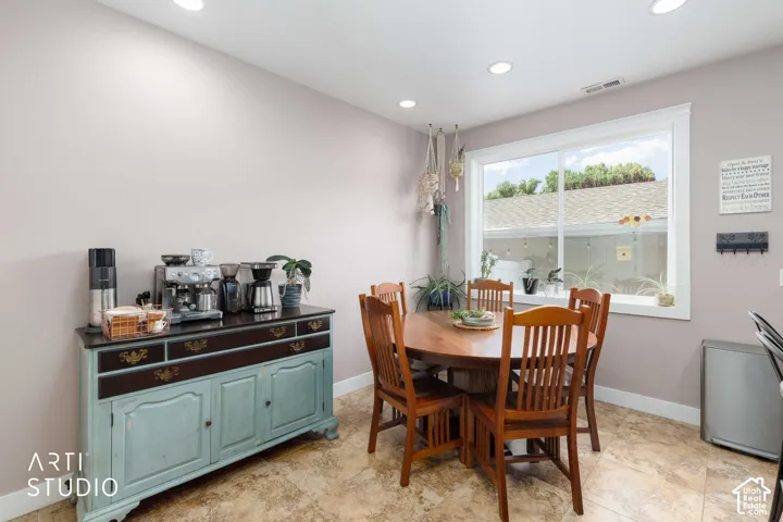 Recessed lighting, large window with white trim, tan tiled flooring, and light gray walls