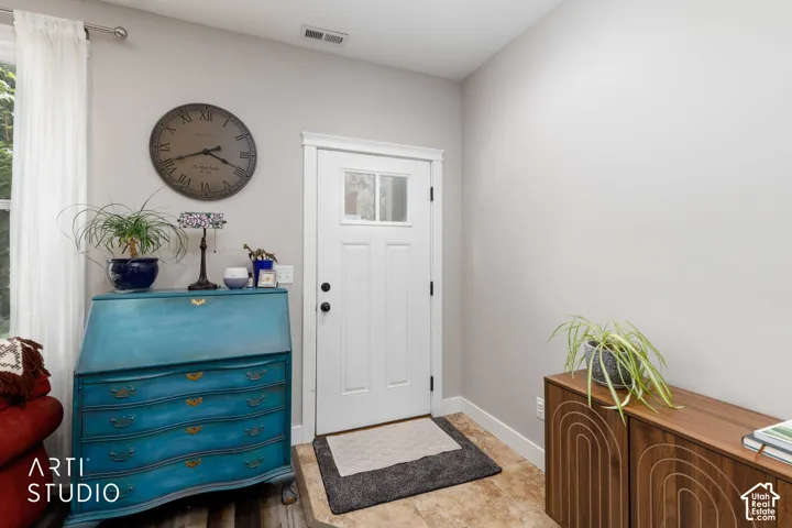 Entryway with a white paneled door featuring a window insert and dark hardware