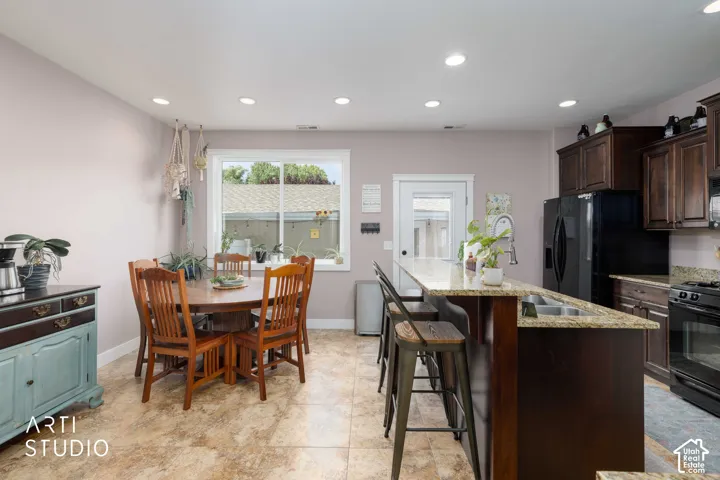 Recessed lighting, wood-finish cabinetry, granite countertops, and black appliances