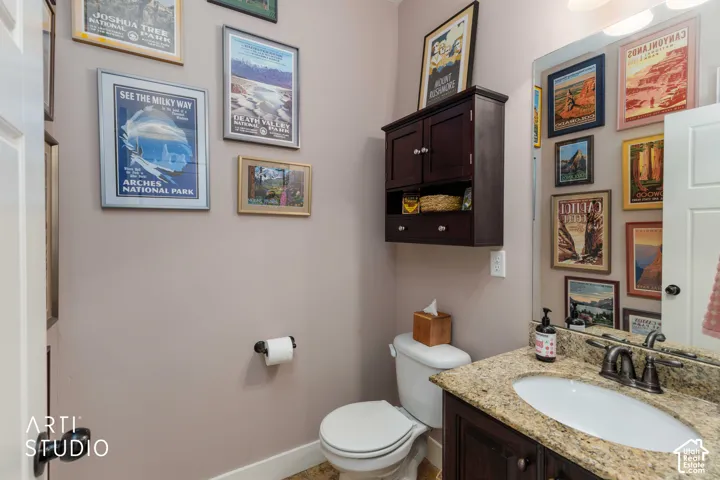 Bathroom with a built-in wood vanity, stone countertop, undermount sink, and wall-mounted storage cabinet
