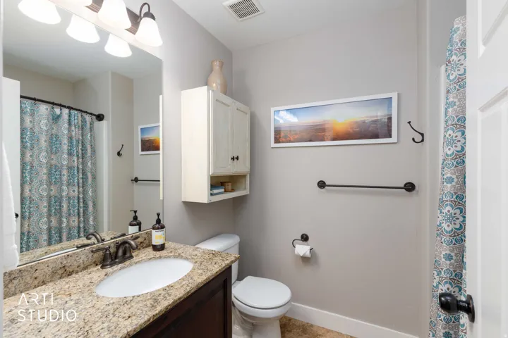 Vanity with a granite-style countertop, undermount sink, and bronze-finish faucet