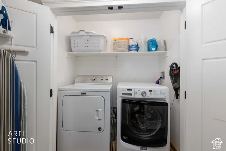 Integrated laundry closet with built-in shelving, white paneled doors, and a light-colored flooring