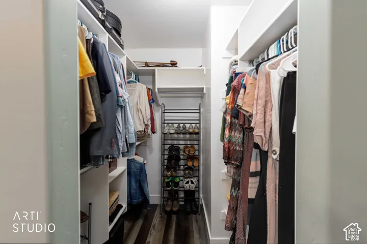 Walk-in closet featuring built-in shelving, hanging rods, and wood-finish flooring
