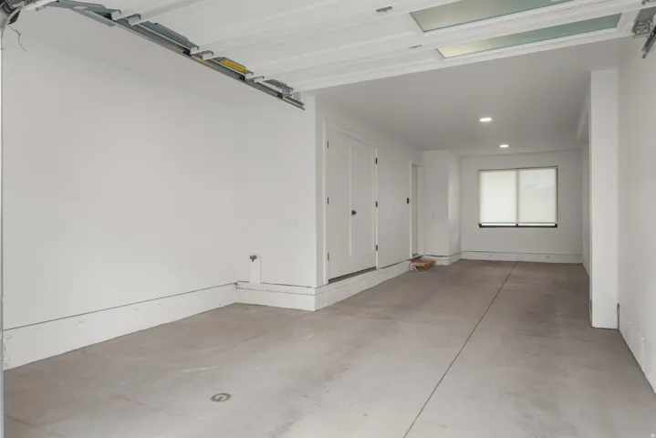 Spacious garage with concrete flooring, recessed lighting, and a rear window with roller shades
