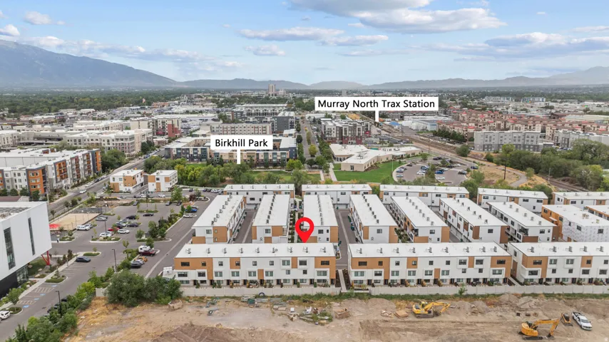 Modern townhome community with flat roofs, multi-level structures, and a mountain backdrop