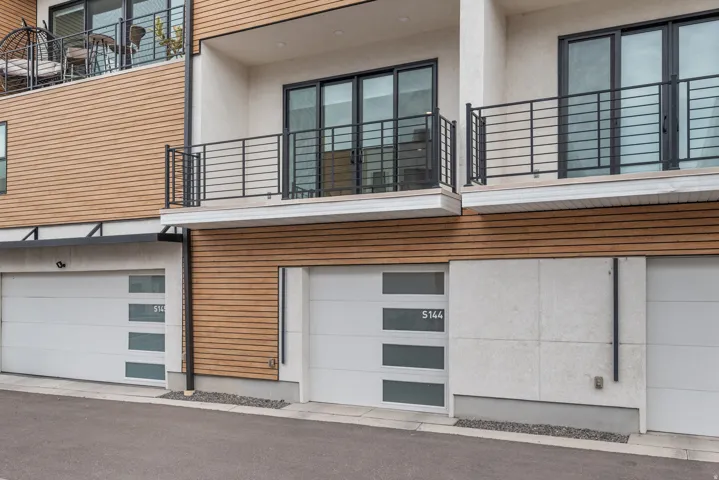 Modern exterior featuring light-toned horizontal siding, concrete accents, and sleek black railings