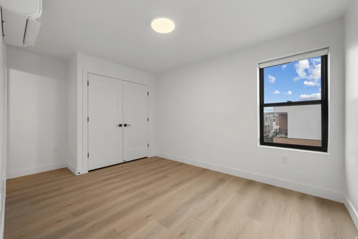 Guest Bedroom - Wood-finish flooring, white walls, and a window with a dark frame