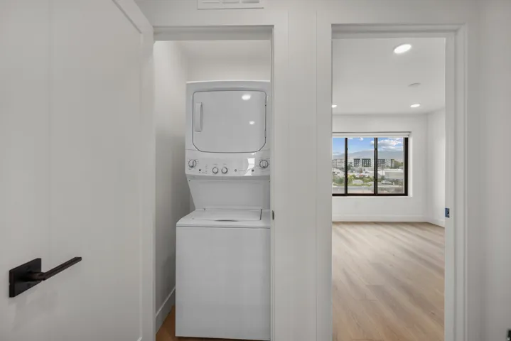 Stackable washer and dryer, recessed lighting, wood-finish flooring, and large window with exterior scenery