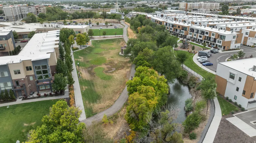 Aerial view showcasing mature landscaping with native trees and vegetation, a meandering water feature, and manicured lawn areas