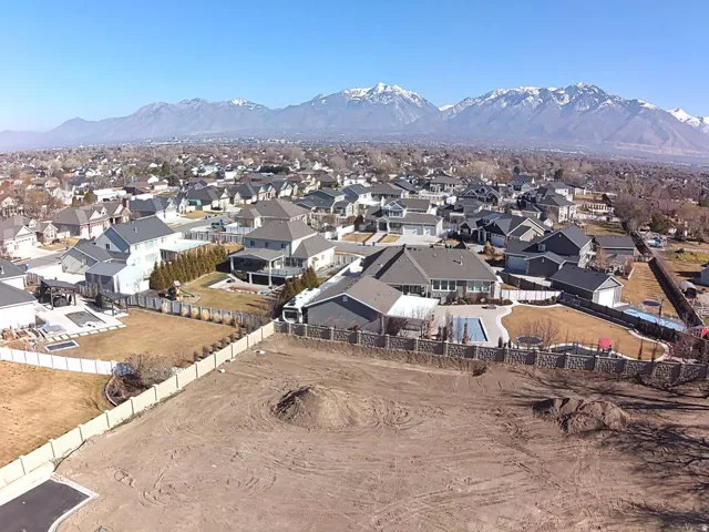 Expansive lot with cleared terrain, surrounded by established residential properties and distant snow-capped mountains