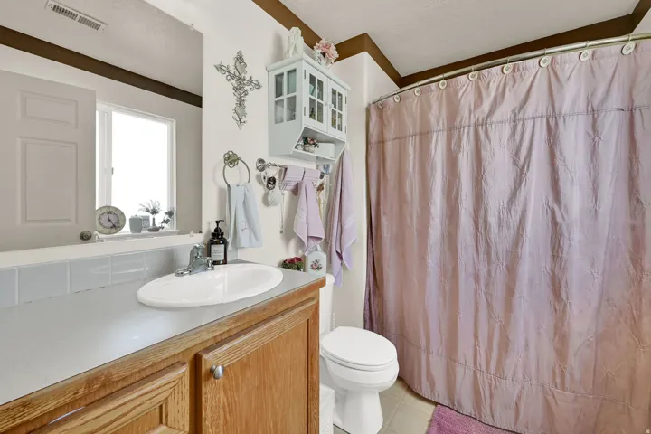 Bathroom featuring a wood-finish vanity with an integrated sink, a large wall mirror, and a window
