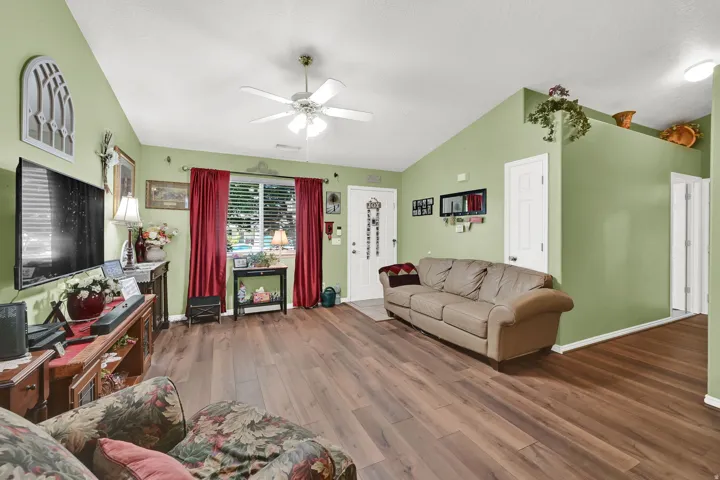 Vaulted ceiling, wood-finish flooring, ceiling fan, and white interior doors
