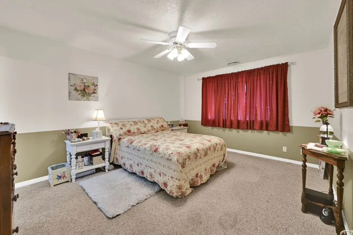 Recessed window with full-length drapery, ceiling fan, and wall-to-wall carpeting