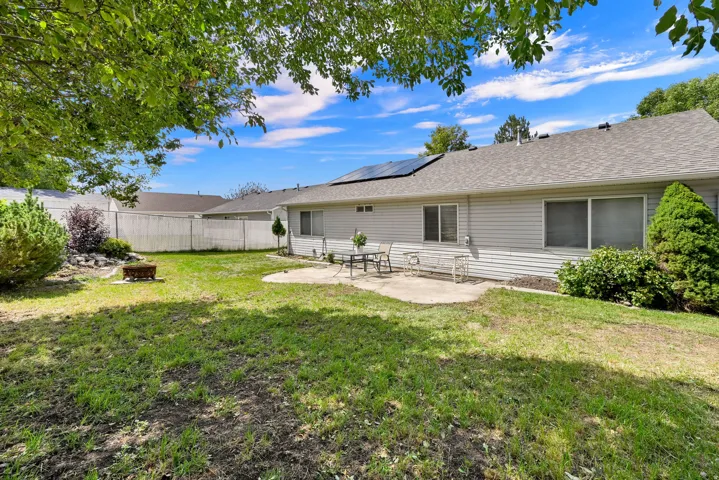 Expansive backyard featuring a concrete patio, a fire pit, and mature perimeter landscaping