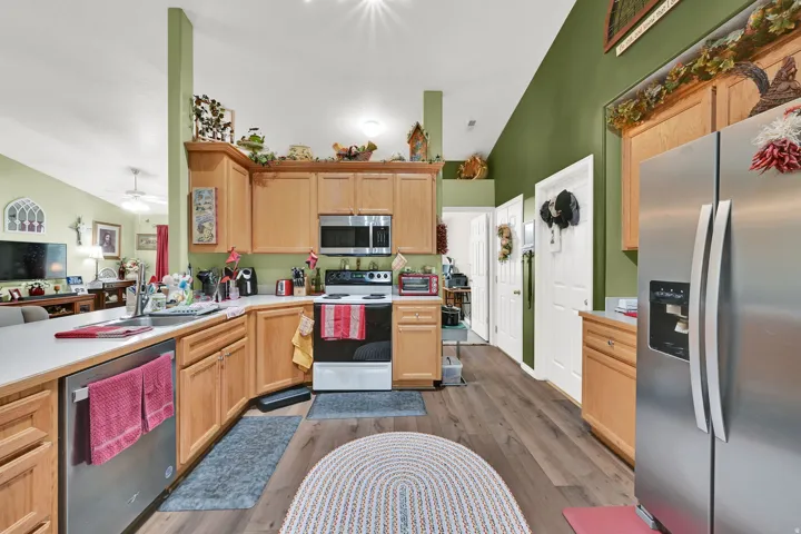 Chef's kitchen featuring warm wood cabinetry, stainless steel appliances including a gas range and side-by-side refrigerator, quartz countertops, and an island workspace