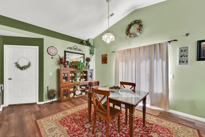 Vaulted ceiling with a central chandelier, wood-finish flooring, and built-in display cabinetry