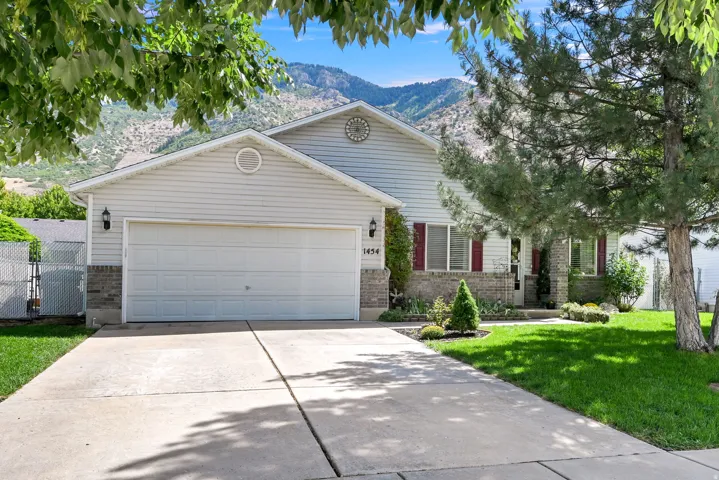 Siding exterior with brick accents, attached garage, concrete driveway, and front lawn landscaping