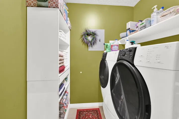 White front-load washer and dryer units, built-in shelving, and white wall-mounted shelving