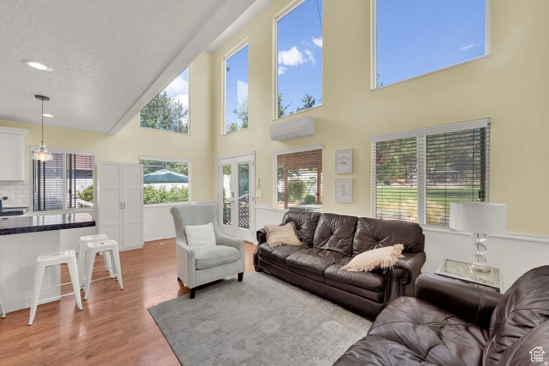 Vaulted ceiling with multiple transom windows, wood-finish flooring, white built-in cabinetry, and a kitchen island with dark countertop