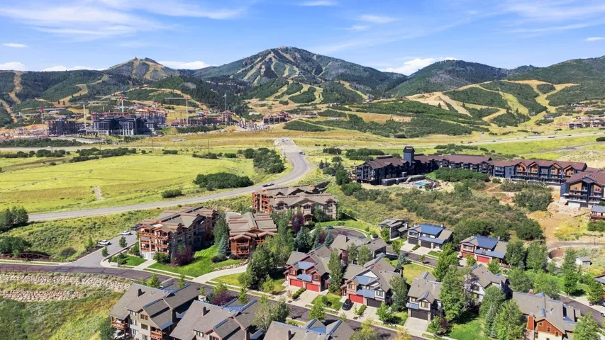 Mountain backdrop with ski slopes and residential developments, surrounded by green hills