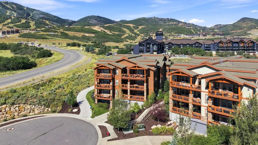 Multi-story residential buildings featuring balconies, surrounded by paved roads and natural landscaping