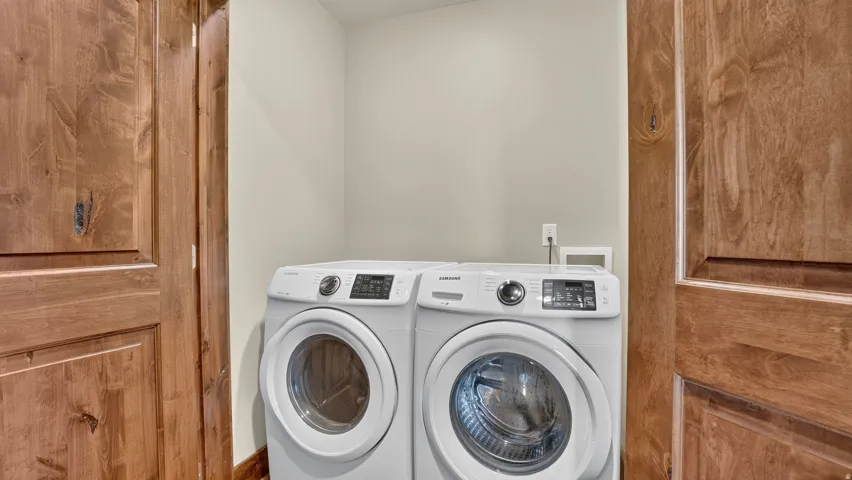 Dedicated laundry area featuring a light wall color and natural wood-finish doors