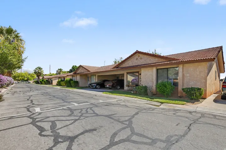 Stucco exterior with a tile roof, mature landscaping, and an attached carport