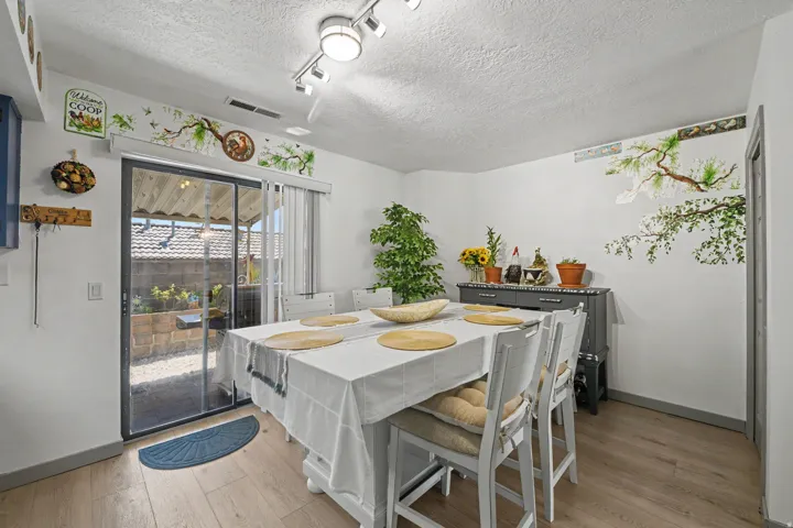 Wood-finish flooring, sliding glass patio door, track lighting, and white walls