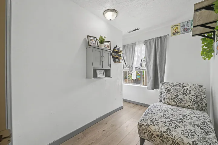 Wood-finish flooring, white walls, and a window with blinds