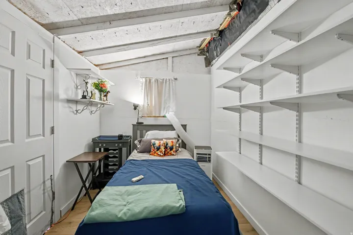 White paneled door, wood-finish flooring, exposed beam ceiling, adjustable wall-mounted shelving