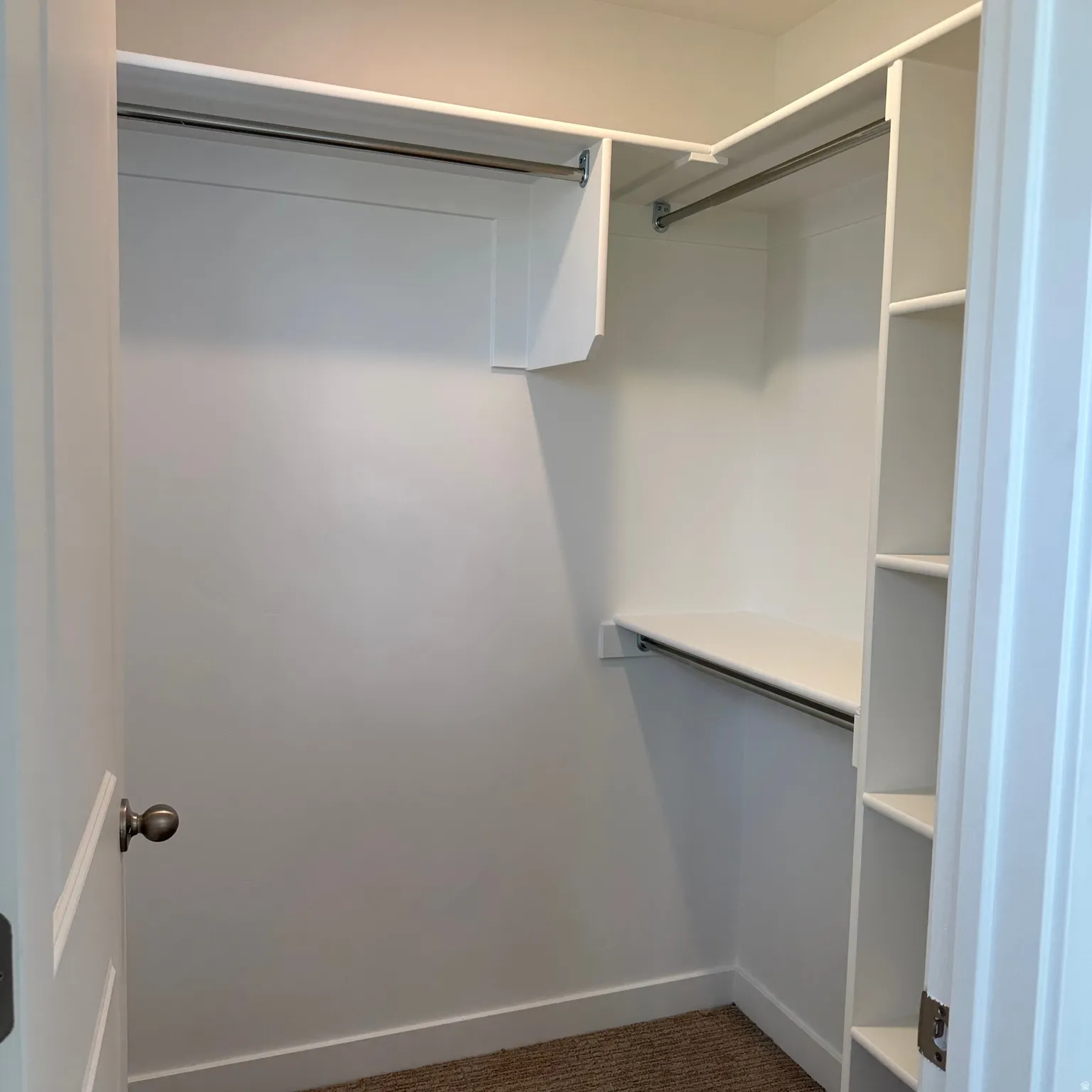 White built-in shelving, white walls, and warm-toned carpet