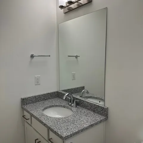 White vanity with silver-tone pulls, a granite-finish countertop, and an undermount sink