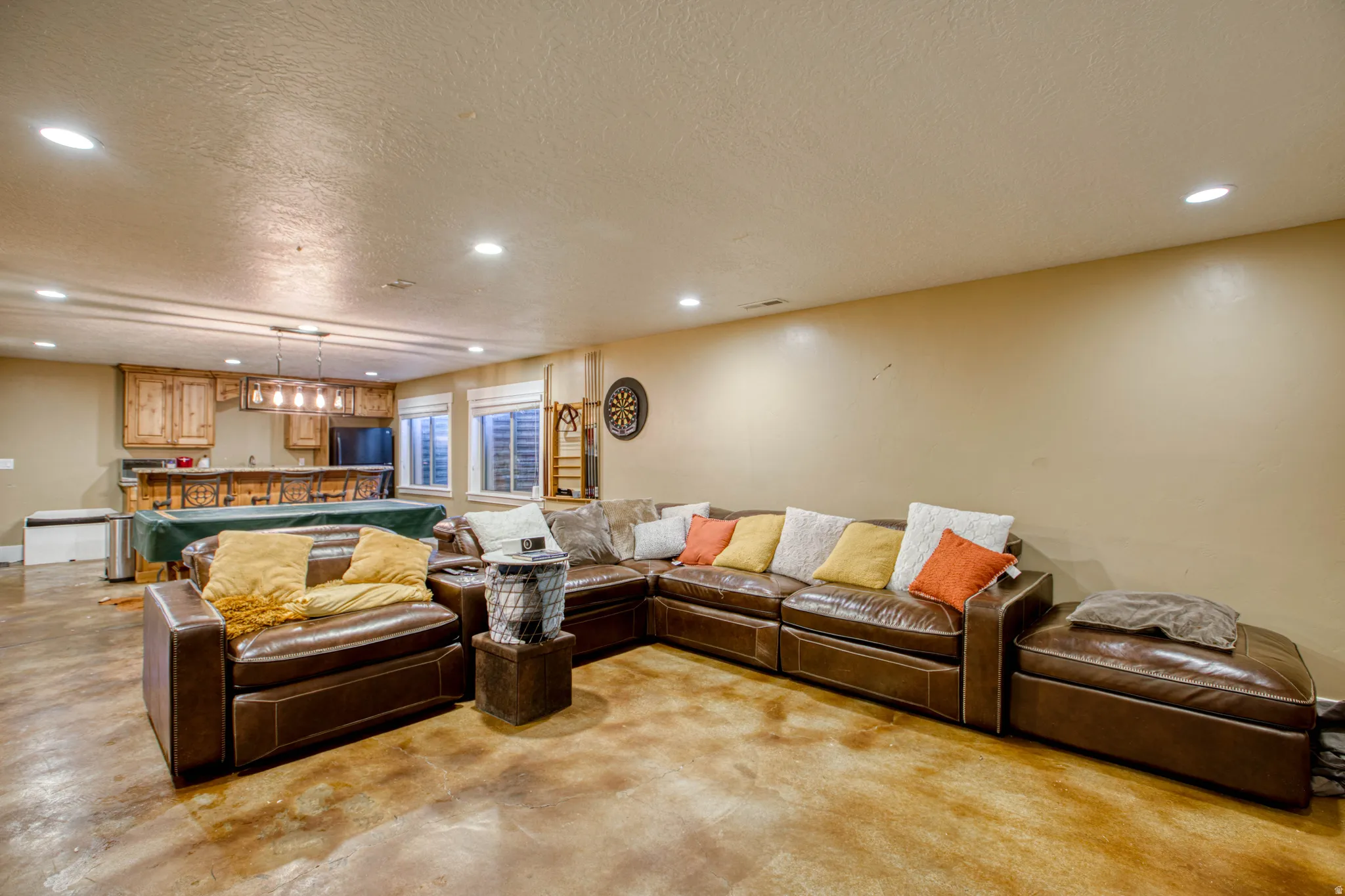 Recessed lighting, wood-finish flooring, built-in wet bar with wood cabinetry, and multiple windows