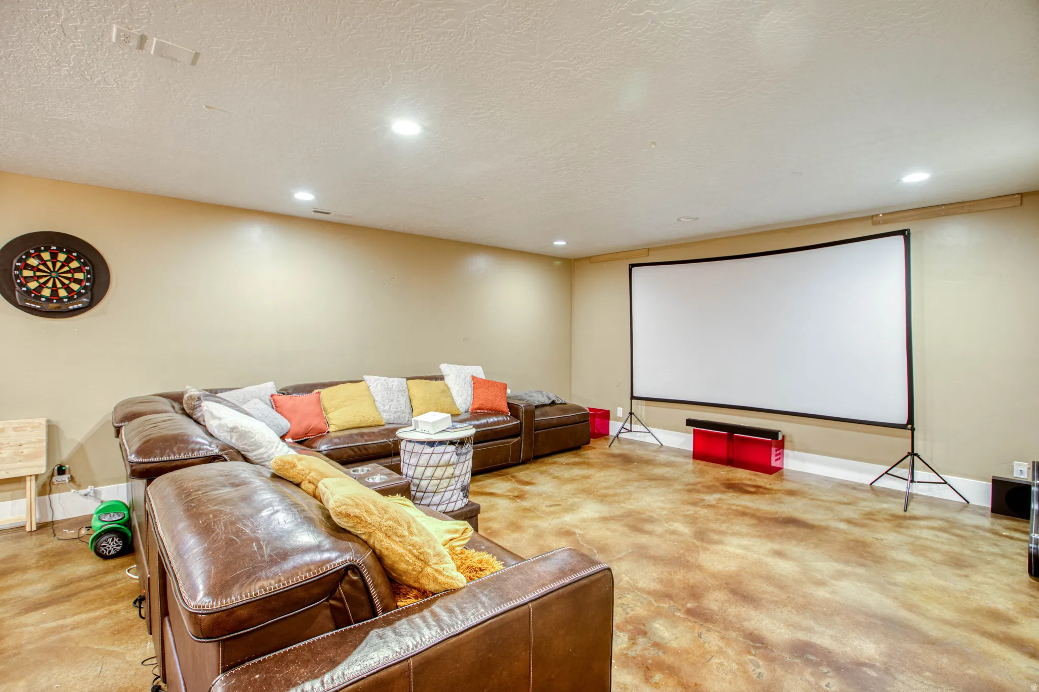 Spacious room featuring a projector screen, recessed lighting, and a durable floor finish