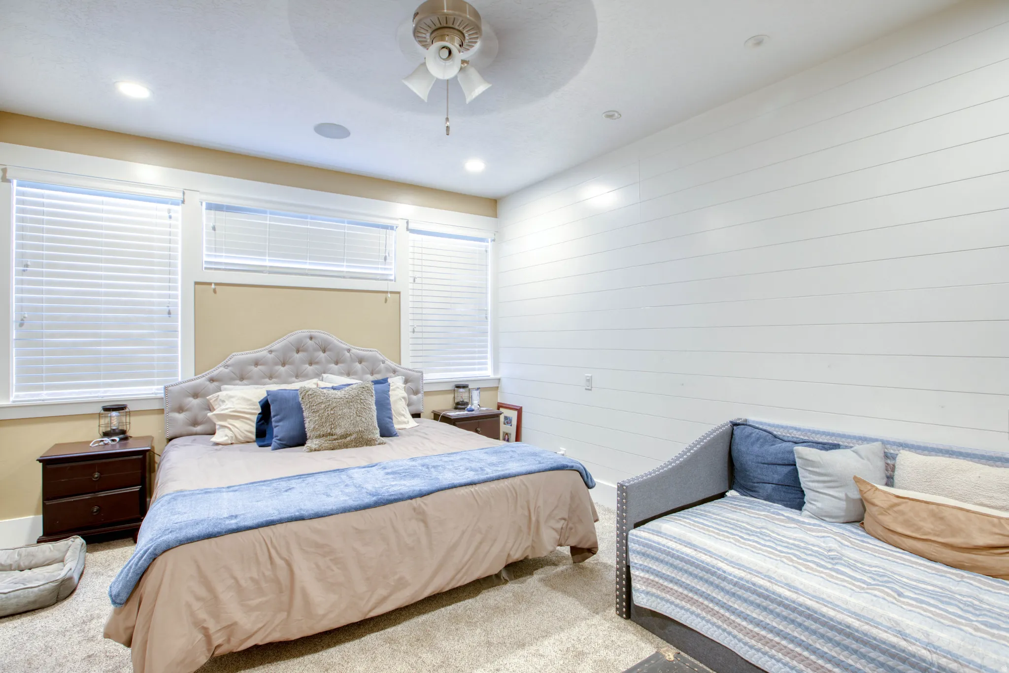 Recessed lighting, ceiling fan, white shiplap accent wall, and multiple windows with blinds