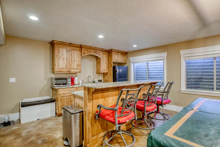 Kitchenette featuring wood-finish cabinetry, granite-style countertops, and a built-in sink