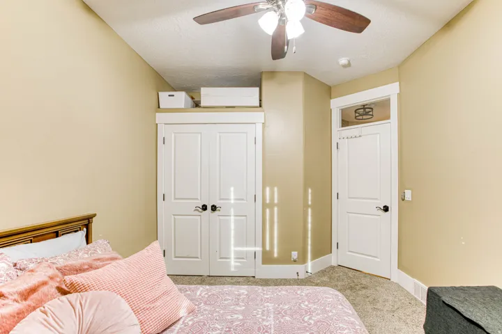 Ceiling fan with light fixture, carpeted flooring, white paneled doors, and transom window
