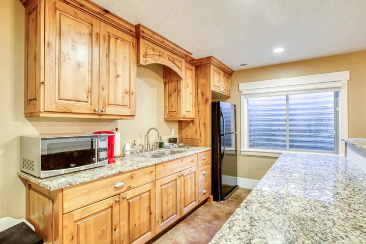 Wood-finish cabinetry, granite countertops, stainless steel sink, and recessed lighting