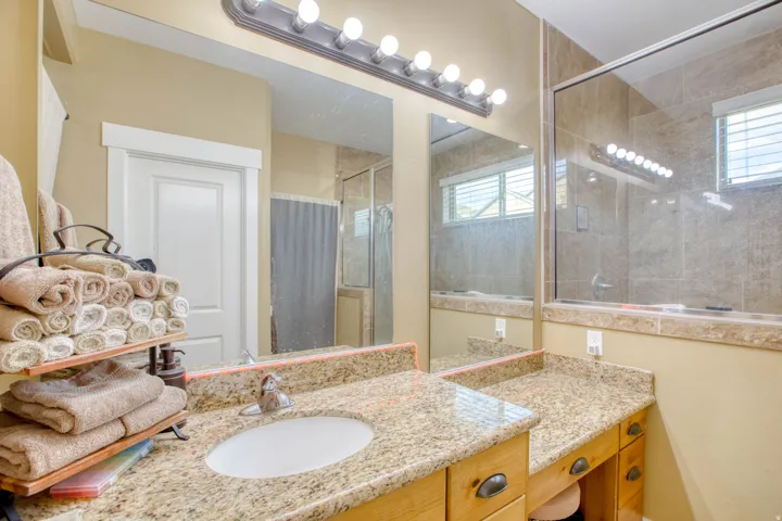 Double vanity with granite countertops, wood-finish cabinetry, and an integrated sink