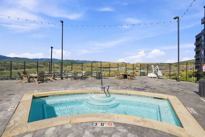 Outdoor spa with integrated steps, surrounding concrete deck, and perimeter fencing
