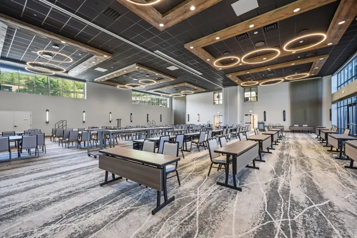 Spacious room featuring high ceilings, a patterned carpet, large windows, and contemporary ceiling light fixtures