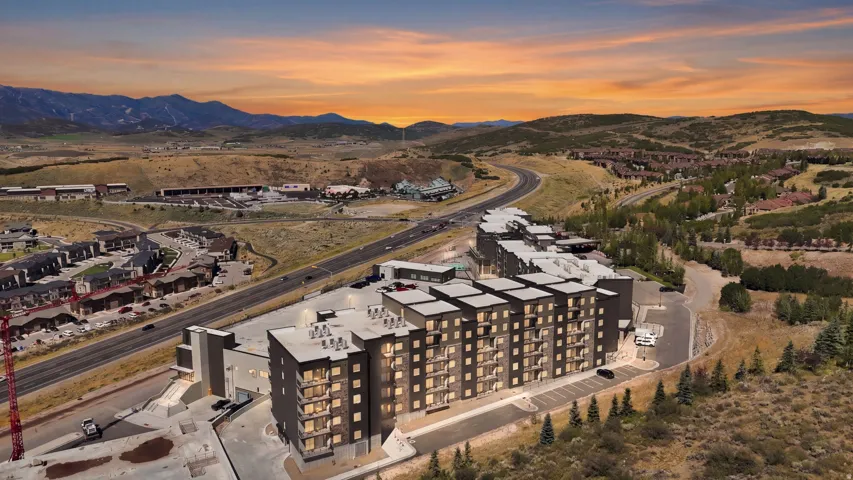 Multi-story residential buildings with balconies, surrounded by paved roads and natural landscaping