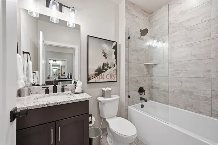 Dark wood-finish vanity with granite countertop, integrated sink, and matte black fixtures
