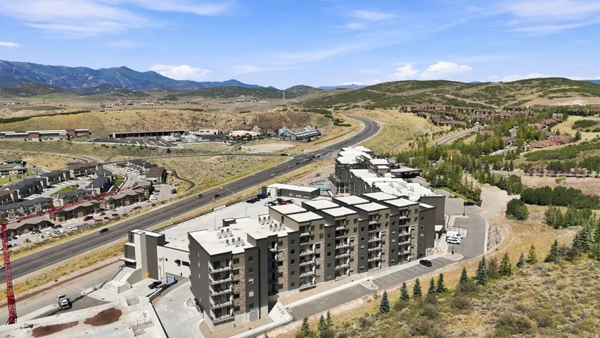 Multi-story building featuring multiple balconies, a flat roof, and a paved parking area