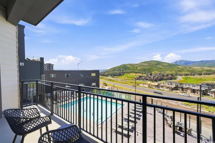 Private balcony with metal railings and concrete flooring, overlooking a swimming pool area