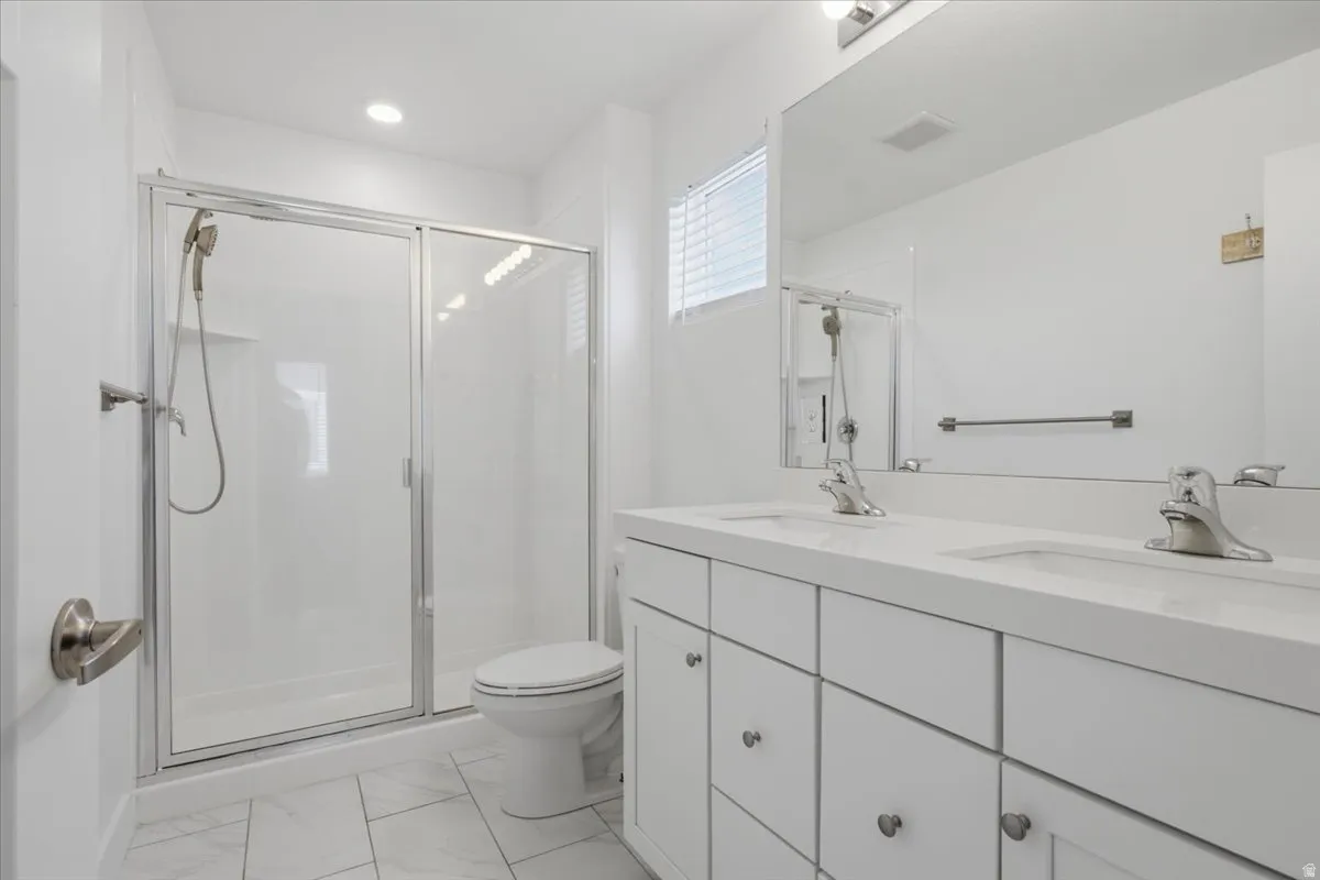 Dual vanity with undermount sinks, frameless mirror, white cabinetry, and brushed nickel hardware
