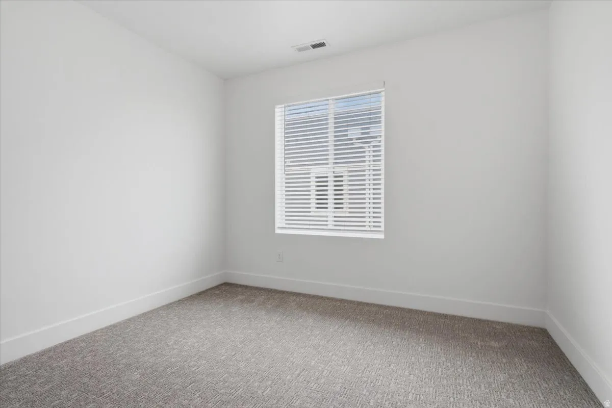 Neutral wall tones, gray carpet flooring, a window with white blinds, and white trim