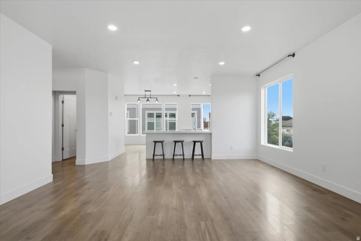 Expansive room featuring wood-finish flooring, recessed lighting, and a large window