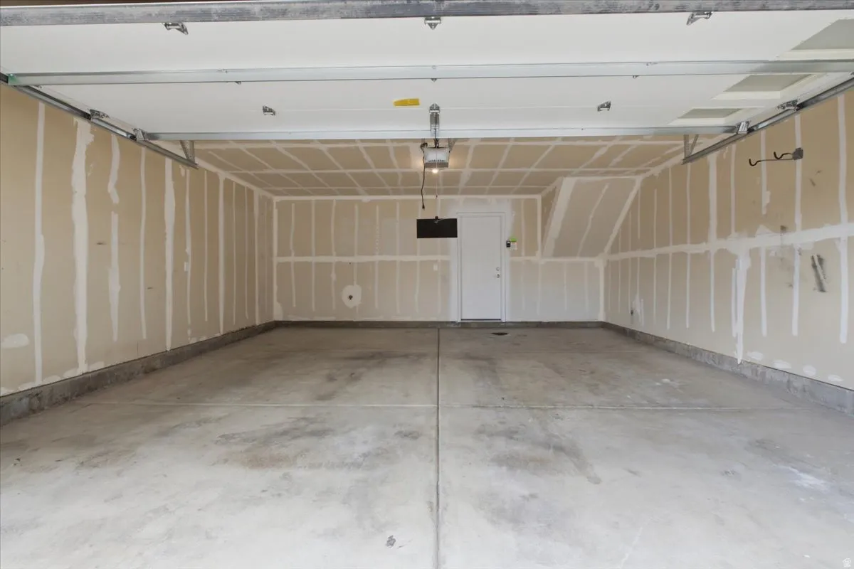 Spacious two-car garage with concrete flooring, unfinished drywall, and a ceiling-mounted light fixture